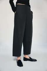 Pantalón de tiro medio con corte tipo ballon, bolsillos delanteros y detalle de pinzas. Cuenta con cierre frontal de cremallera y gancho metálico.