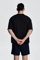 Remera deportiva negra de corte boxy, confeccionada en tejido funcional DryMove™ con efecto lavado. Tiene cuello redondo ribeteado acanalado y hombros caídos.