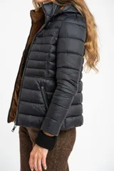 Campera reversible con diseño acolchado, cierre frontal y capucha. Un lado es de color negro y el otro de color tostado, con puños tejidos en color negro.