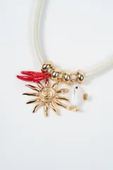 Collar de cordón color crema con dijes colgantes: una pinza de langosta roja, un sol dorado y un pez blanco con detalles dorados, intercalados con cuentas metálicas doradas.