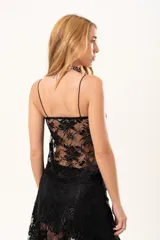 Top de encaje negro con breteles finos, diseño con detalle fruncido en el escote y apertura frontal con nudo decorativo.