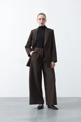 Blazer sastrero negro de doble botonadura con botones marrones, cuello solapa y mangas tres cuartos. Tiene dos bolsillos delanteros con solapa.