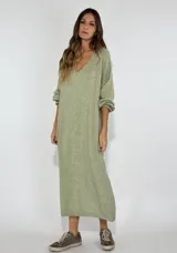 Vestido midi color verde claro, de corte holgado, escote en V y mangas largas con puños elásticos.