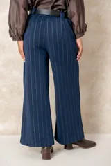 Pantalón de corte ancho y tiro alto, confeccionado en tejido azul marino con finas rayas verticales de hilo de lurex plateado. Presenta cintura con pasacintos y se incluye un cinturón negro con hebilla metálica.