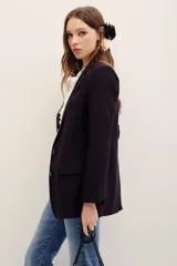 Saco sastrero negro de corte oversize, con solapas clásicas, bolsillos con solapa en los laterales y hombreras incorporadas.