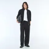 Pantalón de corte ancho y estilo jogging, confeccionado en tejido liso de color negro, con cintura elástica y diseño minimalista.