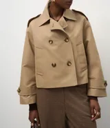 Trench coat corto de la marca Cortelle, confeccionado en una mezcla de algodón y poliéster con estructura de lona. Presenta un diseño de abotonado cruzado, cuello clásico, mangas largas con trabillas en los puños y bolsillos frontales.