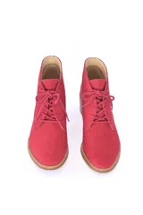 Botin de caña baja con cordones frontales, confeccionado en cuero vacuno liso color rojo granada. Presenta puntera redondeada y tacón bloque de madera clara.