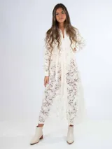 Vestido midi de encaje color crudo, con corte recto, cuello camisero y mangas largas. Incluye cinto de lazo en la cintura y cierre frontal con botones.