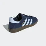 Championes Adidas Handball Spezial, color azul marino con detalles en celeste y suela marrón. Confeccionados en gamuza con las tres tiras clásicas de Adidas en los laterales y el nombre del modelo en dorado.