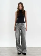 Pantalón de jean de corte wide leg en color gris lavado, con diseño de tiro medio y cierre frontal con botón y cremallera.