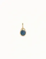 Charm circular bañado en oro, con cristal facetado en color azul zafiro.
