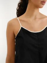 Vestido largo negro de tirantes finos blancos, corte recto y diseño minimalista.