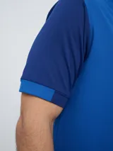 Remera polo deportiva Umbro del Club Nacional de Football, color azul con cuello en V y detalles en rojo y blanco. Incluye el logo de Umbro y el escudo del club.