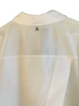 Camisa blanca de popelina con manga larga, cierre con botones delanteros y bordado en contraste en la espalda con la frase 'Love yourself'.