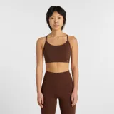 Top deportivo New Balance de soporte ligero, diseñado para yoga y actividades de bajo impacto. Presenta un diseño de estilo jersey con tirantes finos y espalda cruzada, banda elástica inferior para mayor ajuste y logo de la marca en el frente.