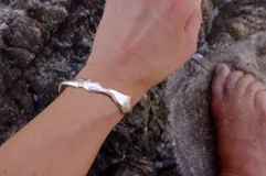 Brazalete rígido abierto de bronce con textura irregular.