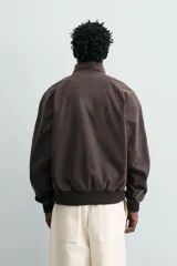 Cazadora de corte relajado color verde militar, con cuello subido, cierre frontal con cremallera y bolsillos laterales con solapa. Presenta puños y ruedo con acabado en rib.