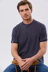 Remera estilo polo con cuello mao y manga corta, de color bordó con detalles en azul en los bordes de las mangas y cuello. Cuenta con cierre frontal parcial de tres botones y pequeño logo bordado en el pecho.