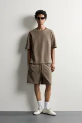 Bermuda estilo jogger de ajuste relajado, confeccionada en tejido interlock de algodón. Cuenta con cintura elástica ajustable con cordón, bolsillos frontales de vivo y diseño liso.