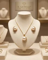 Set de joyería compuesto por collar y aros, elaborados en plata 925 con baño de oro. El diseño presenta una media perla central rodeada por un arco de circonias brillantes.