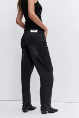 Pantalón de jean color negro lavado, de corte holgado y tiro medio, con costuras reforzadas en las rodillas.