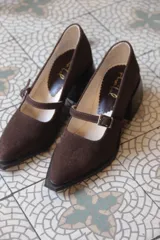 Mocasines de cuero color marrón chocolate, con punta fina y tira sobre el empeine con hebilla metálica.