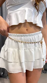 Cinturón plateado de metal con eslabones y dijes colgantes.