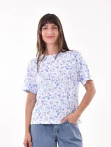 Remera blanca con estampado de paisajes de playa en color azul, cuello redondo y mangas cortas.