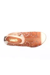 Sandalia baja de cuero color beige con diseño calado de círculos de distintos tamaños en la capellada. Cuenta con una suela de goma con cámara de aire en el talón y cierre posterior.