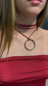 Gargantilla tipo choker de cordón rojo con diseño de múltiples vueltas y dije central de argolla metálica plateada.
