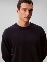 Sweater Calvin Klein de punto color azul marino, con cuello redondo, mangas largas y detalles acanalados en cuello, puños y bajo. Presenta un discreto monograma CK bordado en rojo en el pecho.
