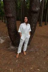 Mono blanco de gabardina de algodón, corte clásico con cierre frontal, pantalón largo con bolsillos, manga corta y cintura fruncida en la espalda.