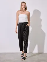 Pantalón negro de satén con pretina elastizada, lazo de ajuste y bolsillos inclinados.