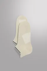 Calcetines de entrenamiento de corte bajo, confeccionados en tejido técnico elástico de color beige. Presentan paneles de refuerzo en la planta y el talón, con detalle de ribete elástico en el borde superior y marca técnica estampada en el lateral.