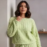 Conjunto de pijama de dos piezas confeccionado en tela tipo plush con textura de puntos en relieve. Incluye una remera de manga larga con cuello redondo y un pantalón a juego, ambos con diseño holgado y abrigado.
