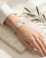 Pulsera de cadena tipo rolo en acero, con placa ovalada central grabada con la frase 'Te quiero Mamá' y dijes de corazón en los extremos.