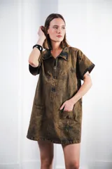 Vestido corto marrón con efecto desgastado, cuello camisero, cierre frontal con cremallera metálica, mangas cortas, dos bolsillos frontales y bordados de soles en el canesú delantero y trasero.