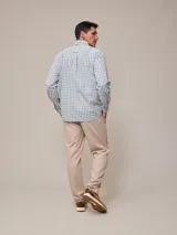 Camisa de manga larga para hombre, confeccionada en algodón con efecto peach (textura suave). Presenta un estampado de cuadros vichy en tonos azul marino y blanco, cuello con botones y un bolsillo de parche en el pecho izquierdo.