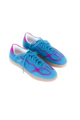Championes de estilo deportivo vintage, confeccionados en cuero vacuno y gamuza. Presentan una combinación de colores azul vibrante con detalles en fucsia intenso, suela plana de goma en tono neutro y logo de la marca grabado en dorado en el lateral.