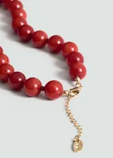 Gargantilla de piedras rojas redondas, engarzadas con hilo rojo y cierre de mosquetón dorado con cadena de alargue.