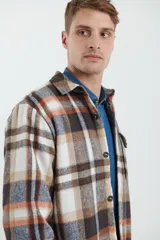 Sobrecamisa de hombre con diseño a cuadros en tonos marrón, beige y blanco. Confeccionada en tejido peludito suave, con cuello clásico, cierre frontal con botones, bolsillo superior y mangas largas con puños abotonados.