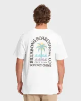 Remera blanca de manga corta con gran estampado en la espalda de diseño tropical, que incluye una palmera, olas y el texto "Billabong Boardshorts Co. Free Since Seventy Three".