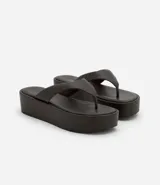 Ojotas negras con plataforma plana, tiras anchas y puntera redonda.