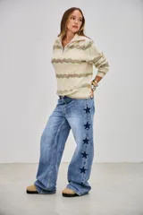 Sweater de punto con cuello alto y cierre frontal, de manga larga. Presenta un patrón de ondas en tonos beige, verde claro y blanco.