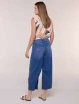 Jean wide leg cropped de tiro medio-alto, confeccionado en denim azul intermedio con efecto degradé y costuras en tono camel. Presenta cinco bolsillos, cierre frontal con botón y cierre, nervaduras decorativas en la zona de las rodillas y ruedo desflecado.