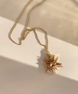 Collar plateado con dije en forma de estrella de puntas irregulares y centro circular.