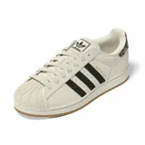 Championes Adidas modelo Superstar, color blanco con las icónicas tres rayas laterales en negro y detalle de estampado animal print en el talón. Presenta la clásica puntera de goma y suela de color caramelo.