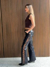 Pantalón de cuero negro con paneles laterales de cuero invecchiato con efecto desgastado. Presenta un diseño de cordones laterales a lo largo de las piernas y ajuste en la cadera, con corte recto y ligeramente acampanado.