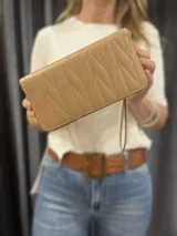 Billetera rectangular color beige con cierre de cremallera y correa de mano. Diseño acolchado con pespuntes diagonales.